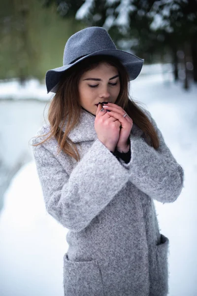 Flicka i grå rock i en snöpark på vintern — Stockfoto