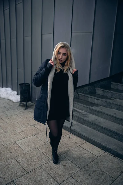 Girl in a black dress in the winter on a background of a dark building — Stock Photo, Image