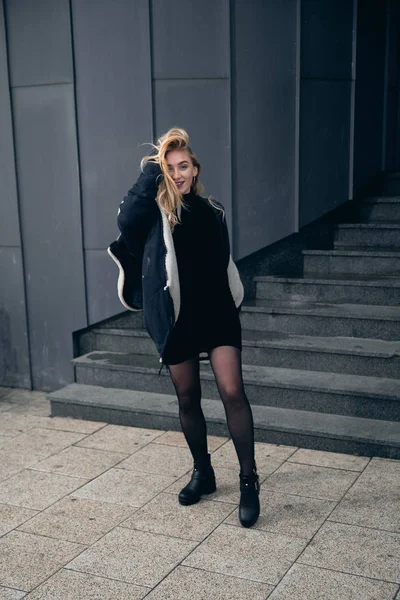 Girl in a black dress in the winter on a background of a dark building — Stock Photo, Image