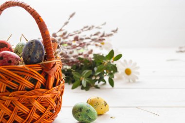 Beyaz ahşap bir arka planda sepetteki paskalya yumurtaları