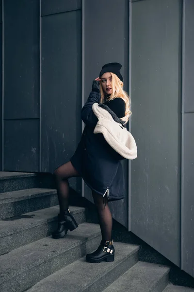 Girl in a black dress in the winter on a background of a dark building — Stock Photo, Image