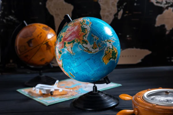 Globe with a barometer and a small plane on the background of a black world map — Stock Photo, Image