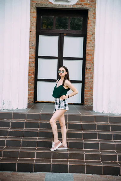 Szexi lány napszemüveg póló és rövid nadrág közelében az oszlopok — Stock Fotó