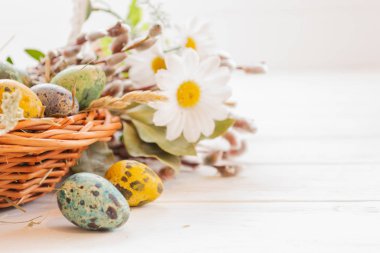 Beyaz ahşap bir arka planda sepetteki paskalya yumurtaları