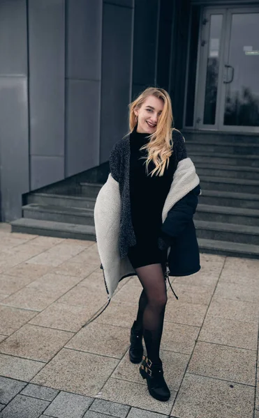 Girl in a black dress in the winter on a background of a dark building — Stock Photo, Image