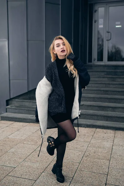 Girl in a black dress in the winter on a background of a dark building — Stock Photo, Image