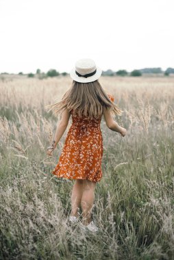 Girl in a red dress on a wheat field