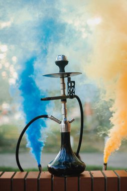 Arka planda renkli dumanlardan oluşan bir nargile.