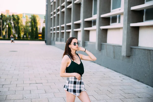 Chica sexy en una camiseta, gafas de sol y mini pantalones cortos cerca de la pared — Foto de Stock