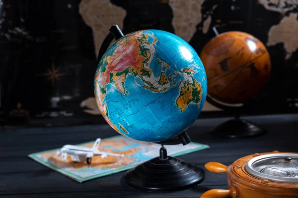 Globe with a barometer and a small plane on the background of a black world map — Stock Photo, Image