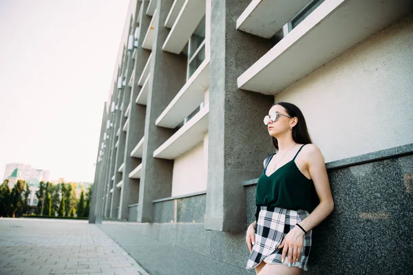 Sexy girl in a T-shirt, sunglasses and mini shorts near the wall — Stock Photo, Image