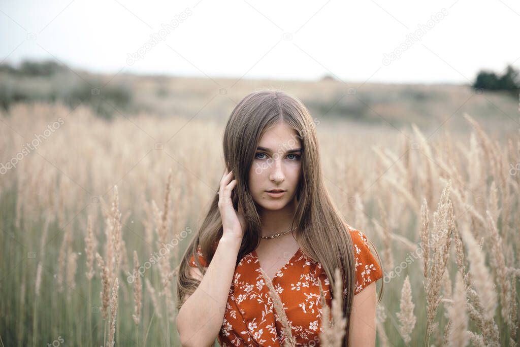 Girl in a red dress on a wheat field