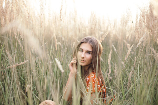 Girl in a red dress on a wheat field.