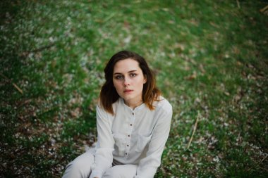 Güzel genç kız bahar parkında dinleniyor ve baharın tadını çıkarıyor.