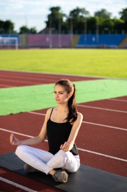 Kız sporcu stadyumda meditasyon yapıyor.