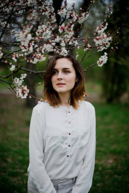 Güzel genç kız bahar parkında dinleniyor ve baharın tadını çıkarıyor.