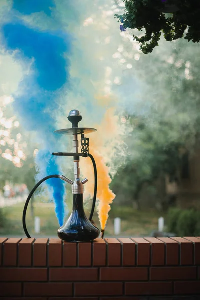 Hookah ao ar livre em um fundo de fumaça colorida — Fotografia de Stock