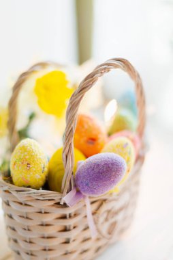 Beyaz ahşap arka planda sepette çok renkli Paskalya yumurtaları.