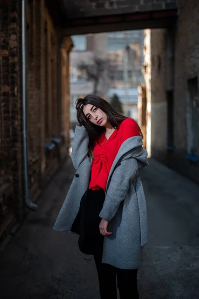 Chica en una blusa roja y un cárdigan gris en el fondo de la vieja pared de ladrillo — Foto de Stock