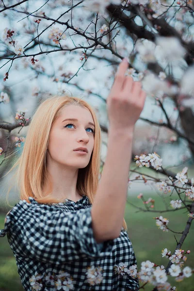 Menina loira bonita em um fundo de árvores floridas — Fotografia de Stock