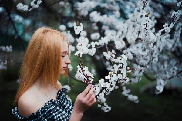 Vacker ung blond flicka på en bakgrund av blommande träd — Stockfoto