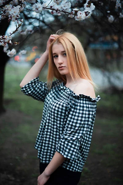 Vacker ung blond flicka på en bakgrund av blommande träd — Stockfoto