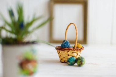 Beyaz ahşap arka planda sepette çok renkli Paskalya yumurtaları.