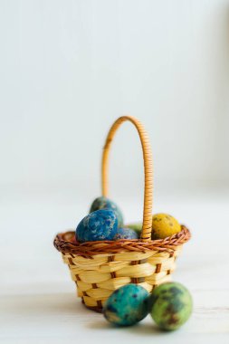 Beyaz ahşap arka planda sepette çok renkli Paskalya yumurtaları.