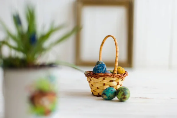 Різнокольорові великодні яйця в кошику на білому дерев'яному фоні — стокове фото