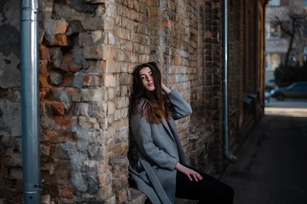 Chica en una blusa roja y un cárdigan gris en el fondo de la vieja pared de ladrillo —  Fotos de Stock