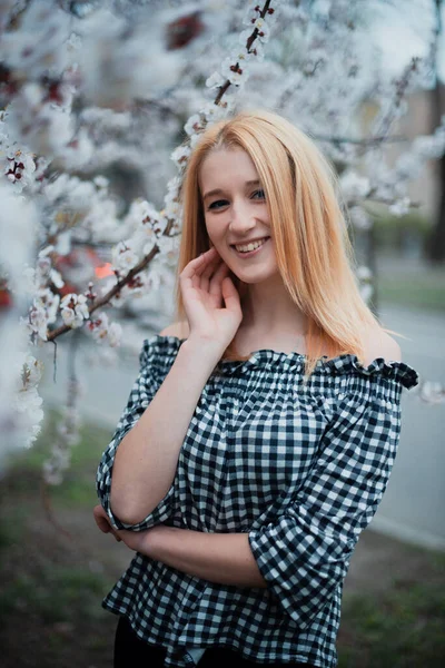 Beautiful young blonde girl on a background of flowering trees — Stok Foto