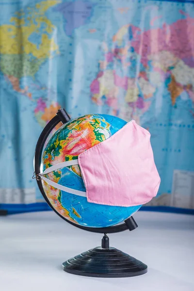 Globe in a medical mask on the background of a blurred world map concept of the global pandemic