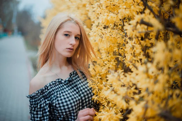 Vacker ung blond flicka på en bakgrund av blommande träd — Stockfoto