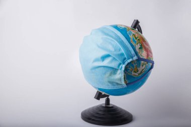 Bulanık bir arka planda tıbbi maske takan bir dünya. Coronavirus pandemik koruma konsepti