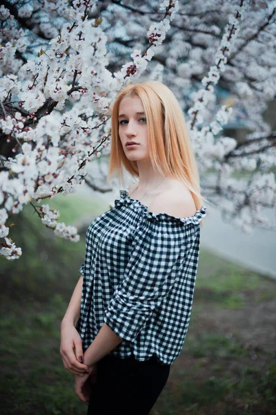 Krásná mladá blondýna dívka na pozadí kvetoucích stromů — Stock fotografie