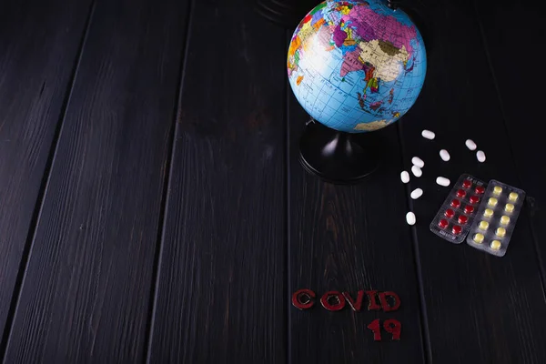 Globe s pilulkami na tmavém rozmazaném pozadí. Světový pandemický koncept COVID-19. — Stock fotografie