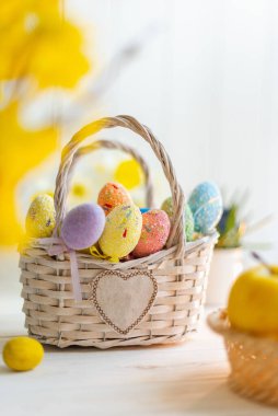 Beyaz ahşap arka planda sepette çok renkli Paskalya yumurtaları.