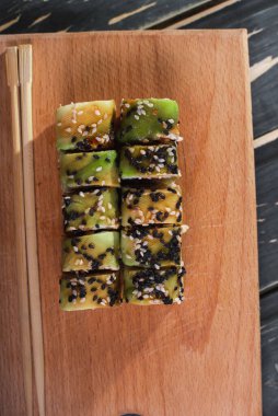 Koyu ahşap arka planda tahta üzerinde somon balıklı suşi.