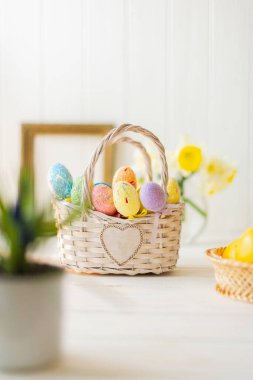 Beyaz ahşap arka planda sepette çok renkli Paskalya yumurtaları.