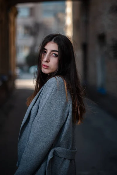 Menina em uma blusa vermelha e um casaco cinza no fundo da parede de tijolo velho — Fotografia de Stock