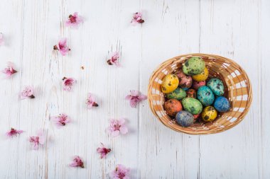 Beyaz ahşap arka planda sepette çok renkli Paskalya yumurtaları.
