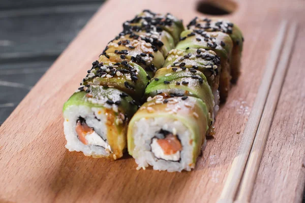 Sushi con salmón sobre tabla de madera sobre fondo de madera oscura — Foto de Stock