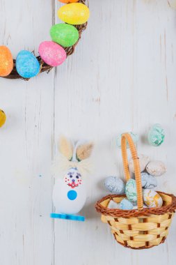 Beyaz ahşap arka planda yumurtaları olan Paskalya tavşanı.