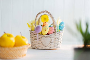Beyaz ahşap arka planda sepette çok renkli Paskalya yumurtaları.