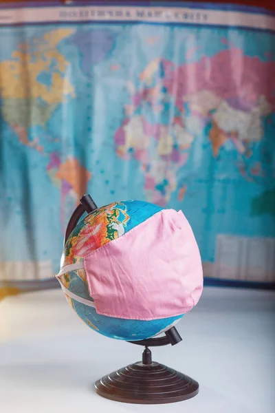 세계적 유행병의 흐릿 한 세계 지도 개념을 배경으로 의료용 마스크를 쓰고 있는 지구본 — 스톡 사진
