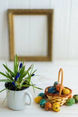 Beyaz ahşap arka planda sepette çok renkli Paskalya yumurtaları.