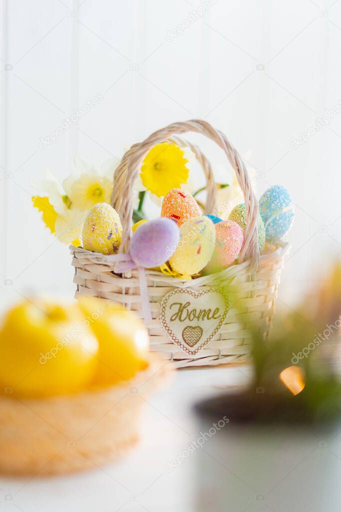 Multi-colored Easter eggs in a basket on a white wooden background