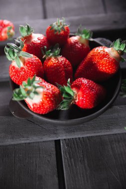 Siyah ahşap arka planda taze olgun çilekler.