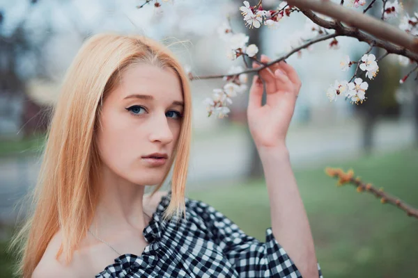 Beautiful young blonde girl on a background of flowering trees — 图库照片
