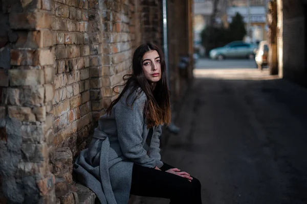 Girl in a red blouse and a gray cardigan on the background of the old brick wall — Stock Photo, Image